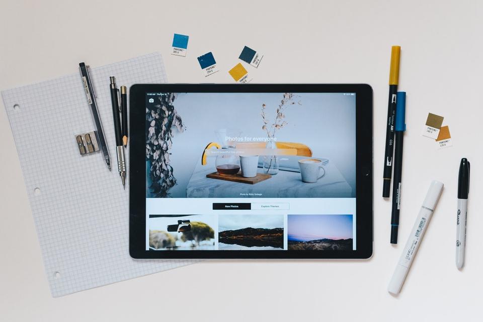 laptop surrounded by pens, paper and color swatches